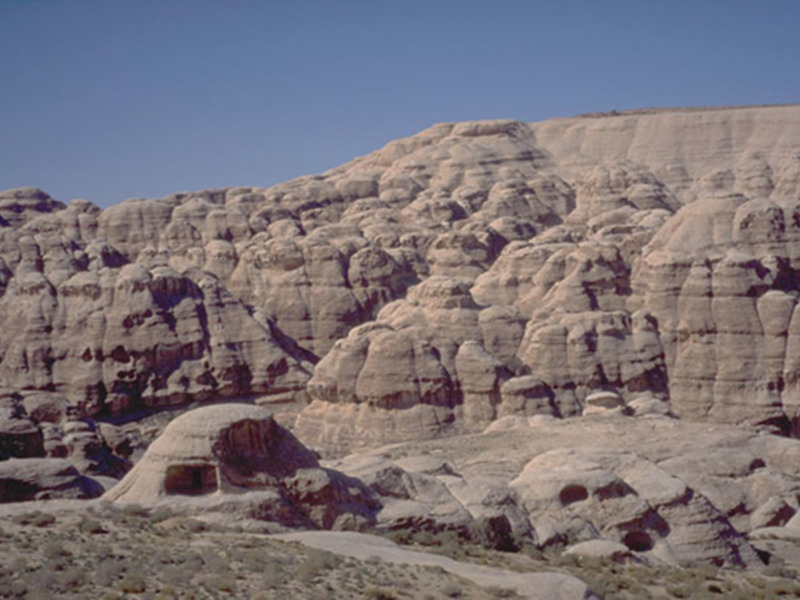Escarpado paisaje rocoso con formaciones erosionadas bajo un cielo azul claro.