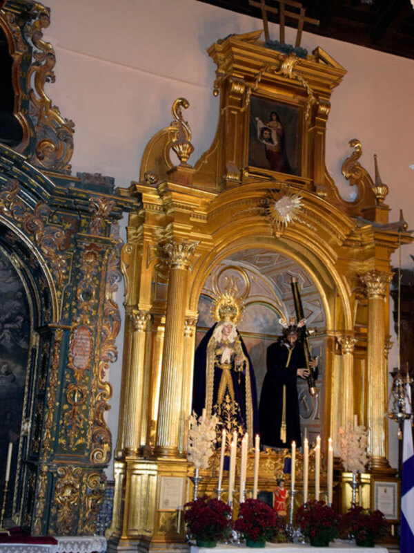 Altar ornado con figuras religiosas y adornos dorados en un templo, destacando la belleza y la riqueza artística.