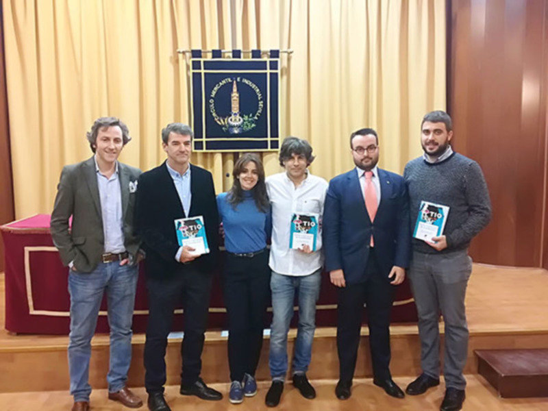 Celebración de un evento académico con cinco personas posando con certificados en un salón formal.