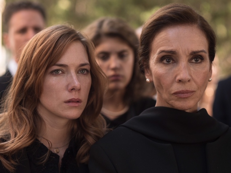 Dos mujeres en un entierro, expresiones serias y tristes.