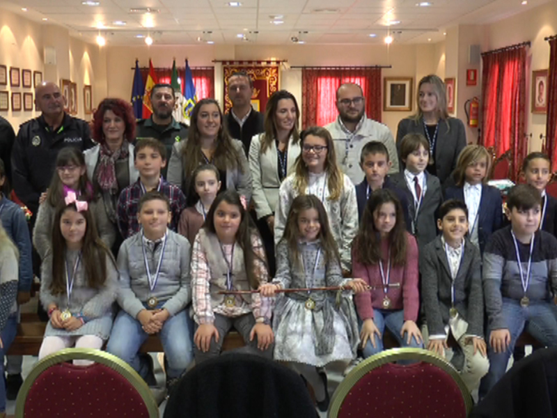 Celebración de logros en una ceremonia oficial con niños y adultos en un salón decorado.