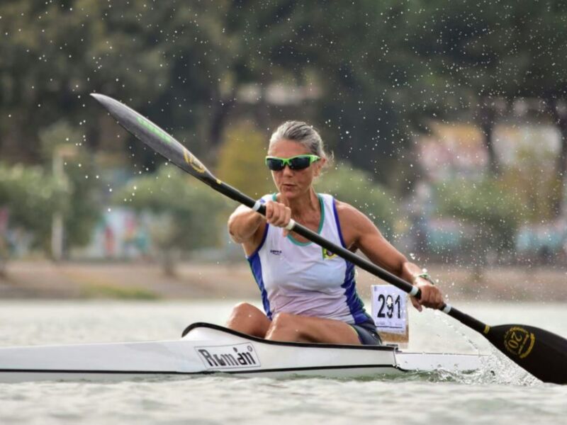 Competitor in a kayak race, wearing a numbered bib and focused on paddling through the water.