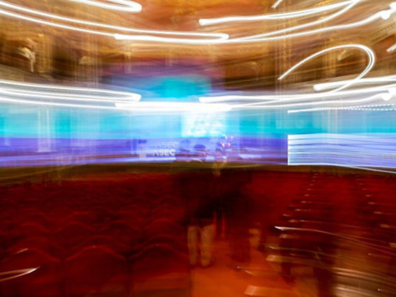 Interior de un teatro con luces de neón y asientos rojos en movimiento borroso.