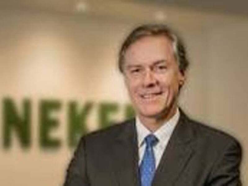 Persona sonriente en traje y corbata frente a un fondo con la marca Heineken.