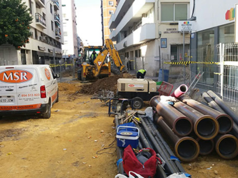 En construcción, un camión MSR con número de matrícula 3465278 y teléfono 910-051-933, junto a maquinaria pesada y tubos de acero.