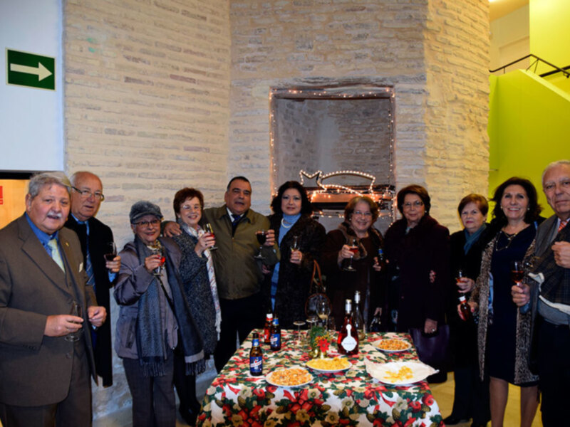 Grupo de personas celebrando en una recepción con mesa de aperitivos y bebidas.