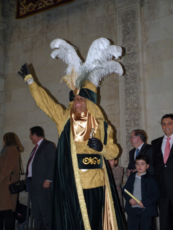 Persona vestida con traje dorado y plumas, celebrando en un evento formal.