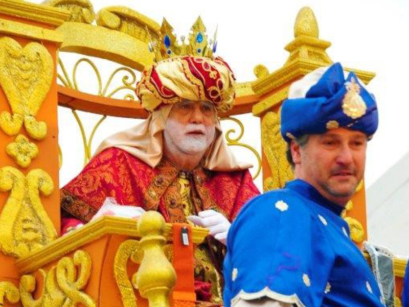 Personajes vestidos con trajes históricos y joyas en un carro dorado, probablemente parte de una celebración o desfile cultural.