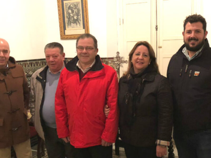 Grupo de personas posando juntos en una sala decorada con pinturas enmarcadas.