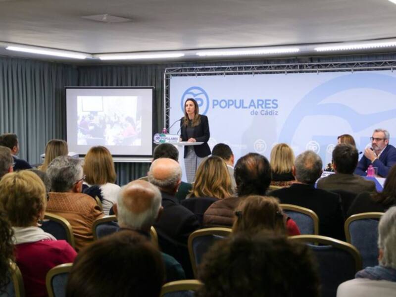 Conferencia de prensa del Partido Popular de Cádiz en un salón lleno de asistentes.