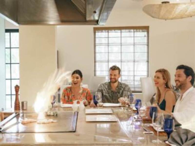Grupo de amigos disfrutando de una reunión en un elegante restaurante, rodeados de luces cálidas y decoración moderna.
