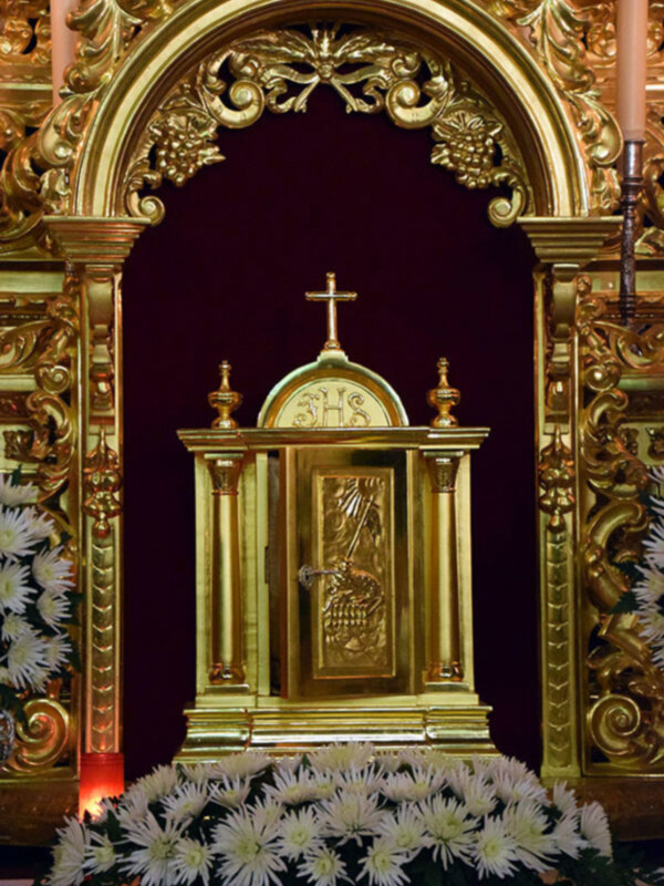 Altar con detalles dorados y flores blancas en primer plano.