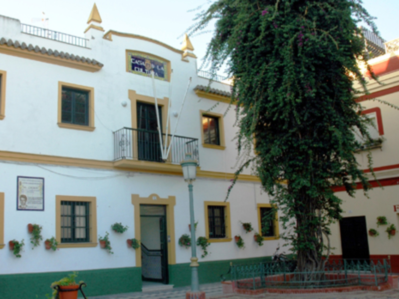 Fachada de una casa con balcones y plantas en Sevilla, España.
