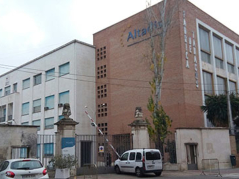 Edificio de Altadis en una ciudad, con vehículos y árboles alrededor.