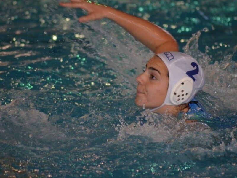 Jugador de waterpolo en acción, número 2, en una piscina iluminada.
