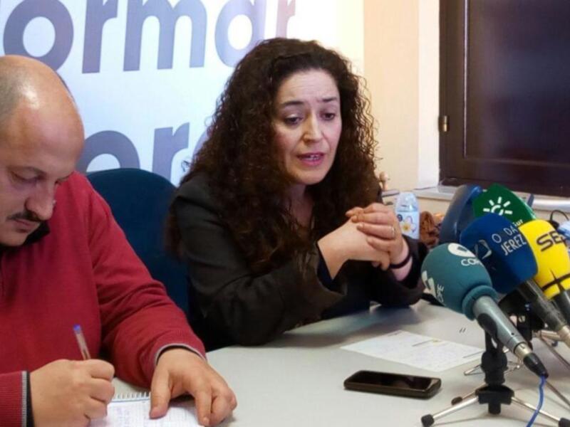 Entrevista en rueda de prensa con micros y documentación en mesa.