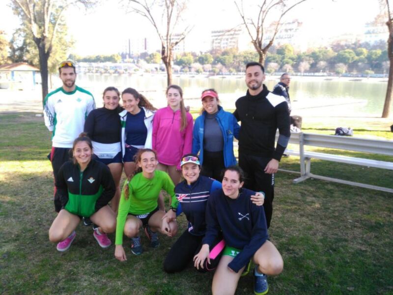 Un grupo de personas posando para una foto en un parque junto a un lago, con vestimenta deportiva y sonriendo.