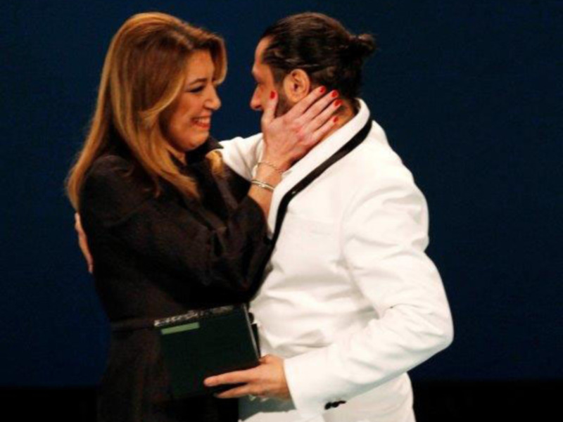 Una pareja abraza emocionalmente en un evento formal.