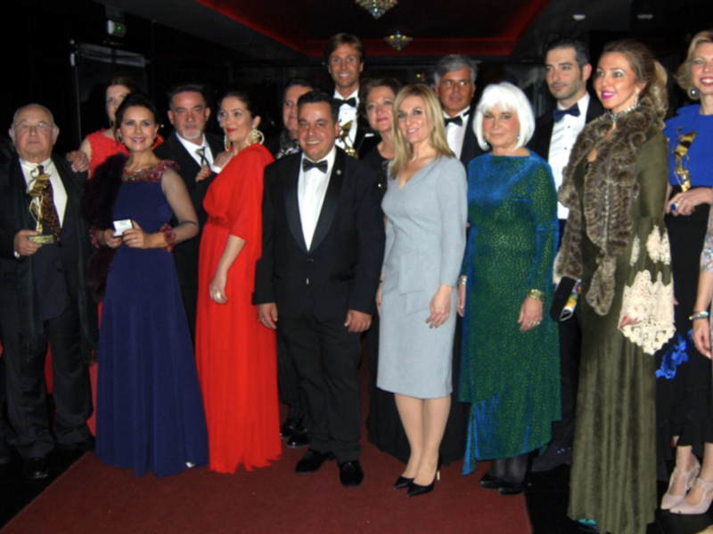 Grupo de personas en trajes formales posando para una foto en un evento nocturno.