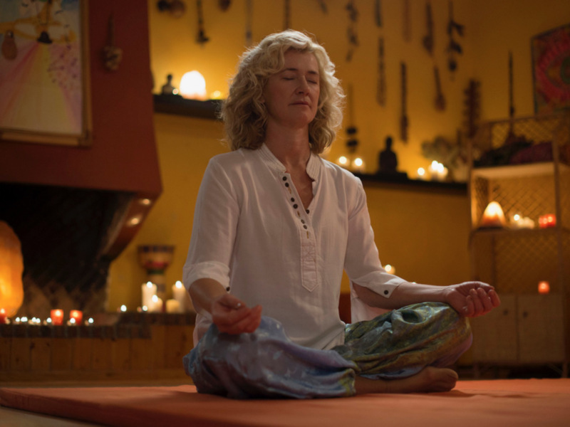 Meditación en un ambiente acogedor con velas y decoración relajante.