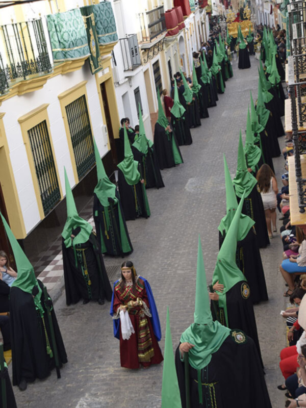 Procession of hooded figures in green and black robes, possibly during a religious or cultural event.