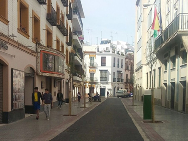 Callejón urbano con edificios de estilo mediterráneo y personas caminando.