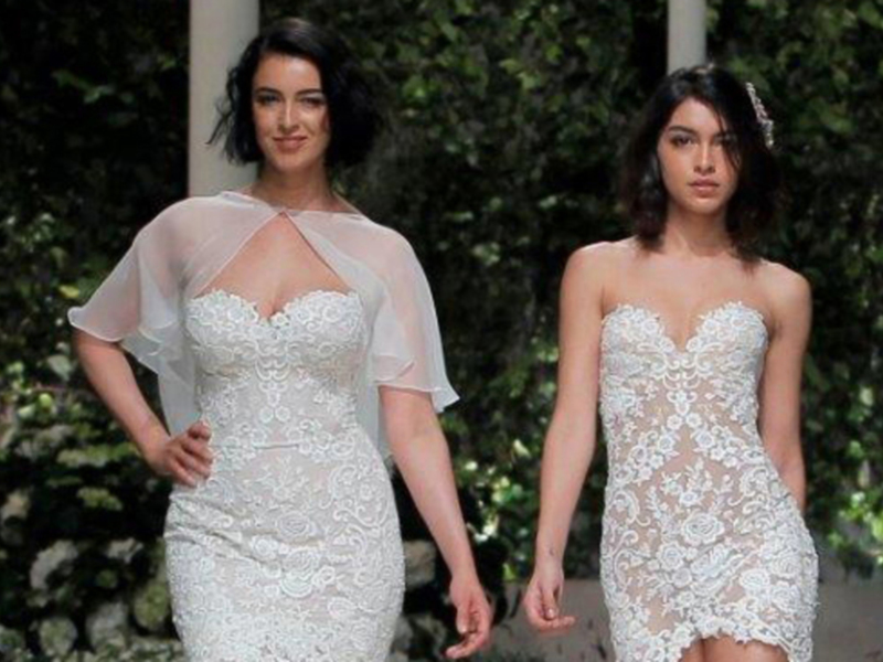 Desfile de moda con modelos en vestidos de encaje blanco, presentados en un entorno al aire libre con vegetación verde.