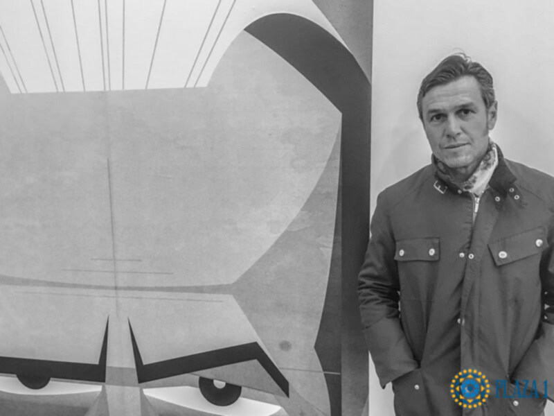 Un hombre posa junto a una imagen de un avión en blanco y negro.