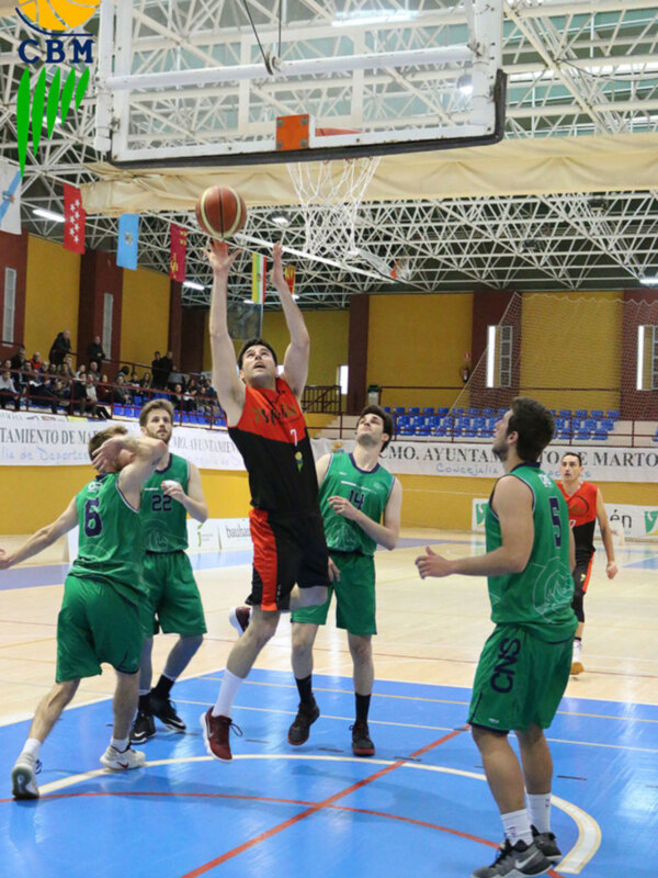 Jugador en acción durante un partido de baloncesto en una cancha deportiva.