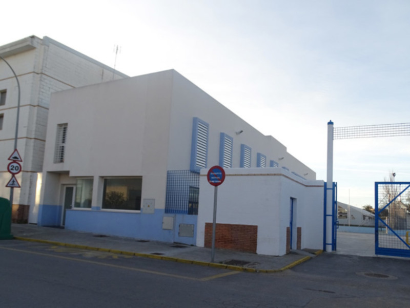 Edificio blanco con ventanas azules y puerta de acceso azul.