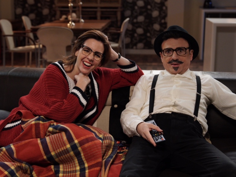 Amigos en casa, disfrutando de la televisión con una manta en el sofá.