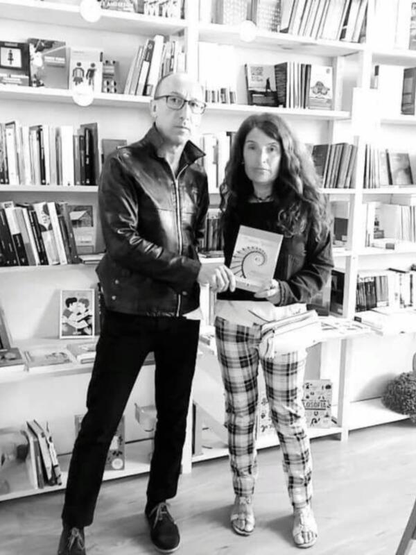 Una pareja posa junto a una estantería llena de libros en un ambiente acogedor.