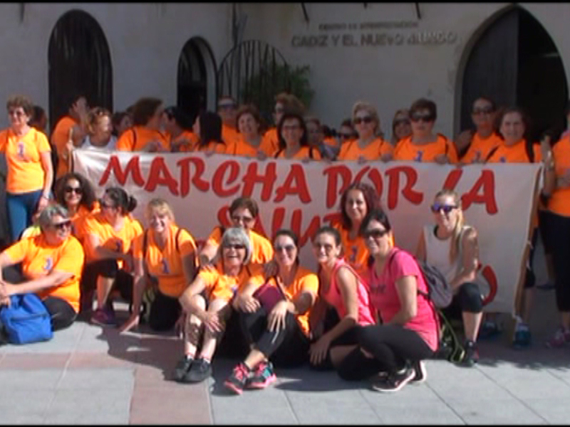 Gruppo di donne in magliette arancioni con striscione che recita "MARCHA POR LA SALUD".