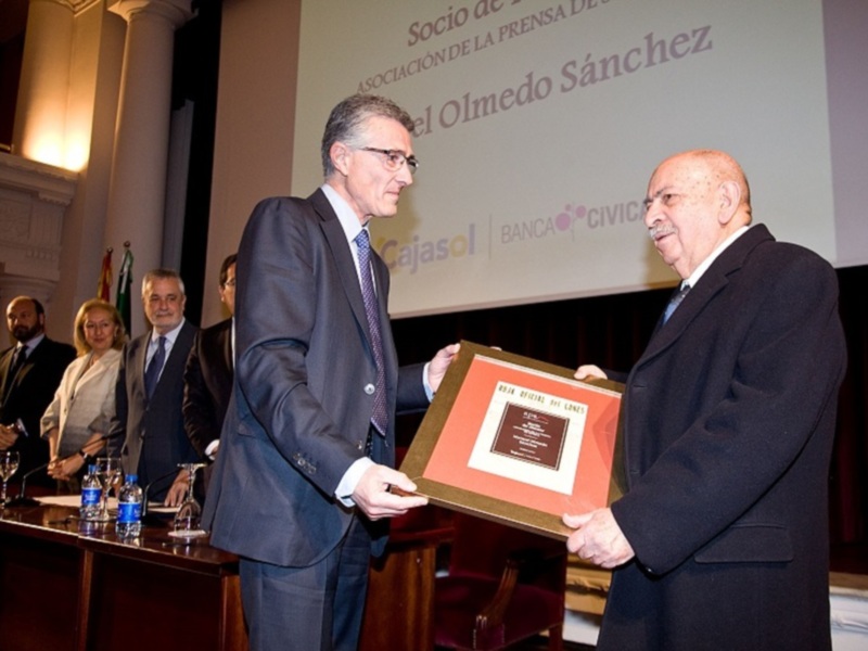 Premio de la Asociación Banca Cívica a Olmedo Sánchez en una ceremonia formal en un salón con columnas y pantalla proyectada.