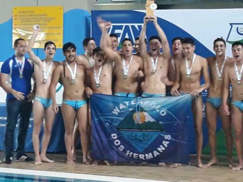 Equipo de waterpolo celebrando en el podio con medallas y trofeo.