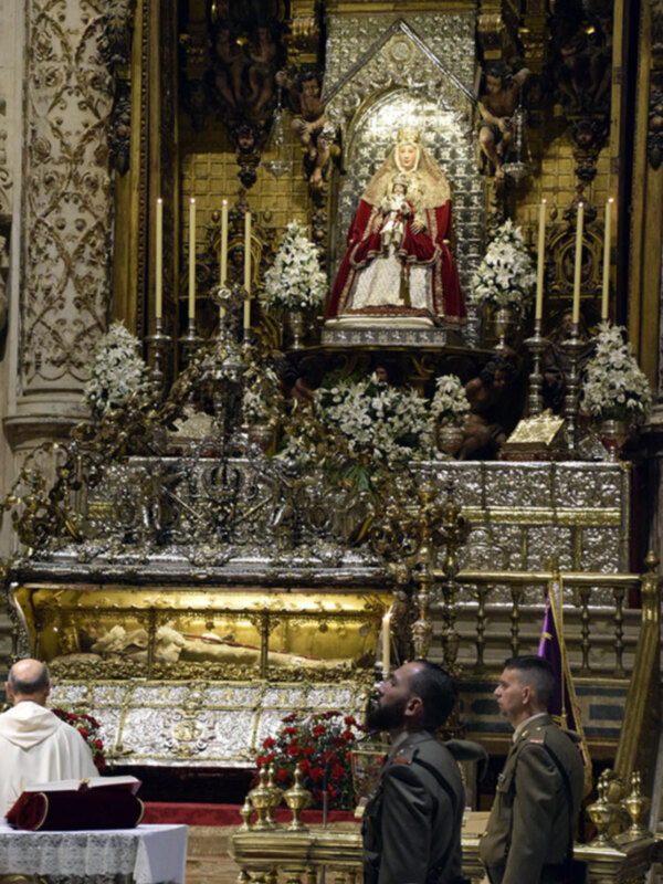Altar con estatua de la Virgen María y decoración floral en un ambiente religioso y ceremonial.