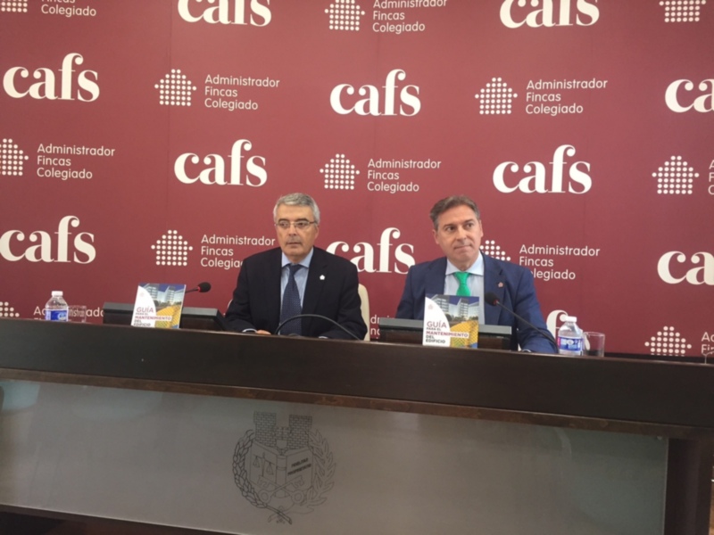 Dos hombres en traje sentados en una mesa con micrófonos, frente a un fondo rojo con el logo de 'cafs' y 'Administrador Fincas Colegiado'.