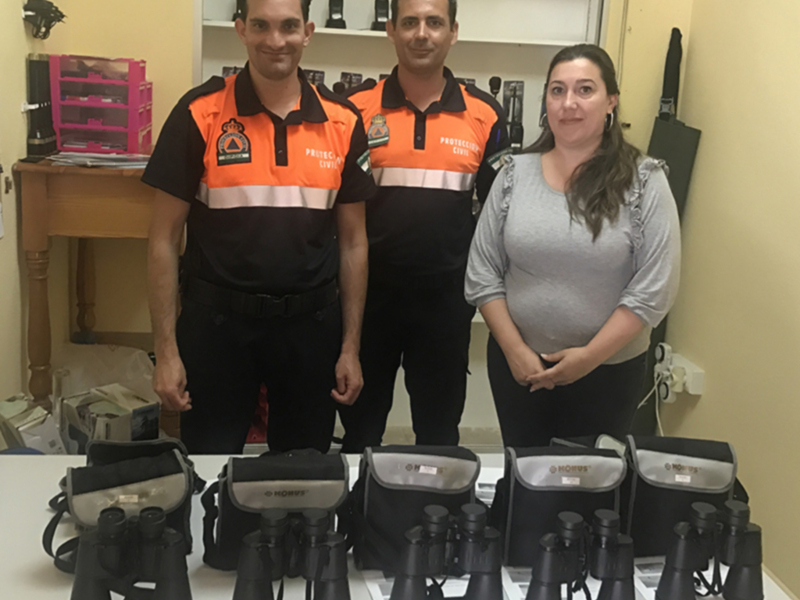 Tres personas en uniforme de Protección Civil junto a varios binoculares de la marca KONUS.