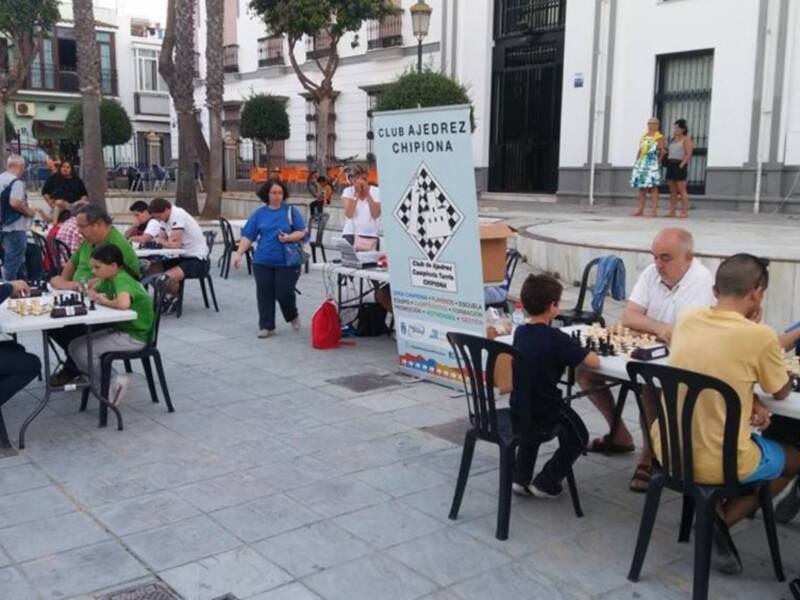 Juegos de ajedrez en la plaza de Chipiona, con participantes de todas las edades.