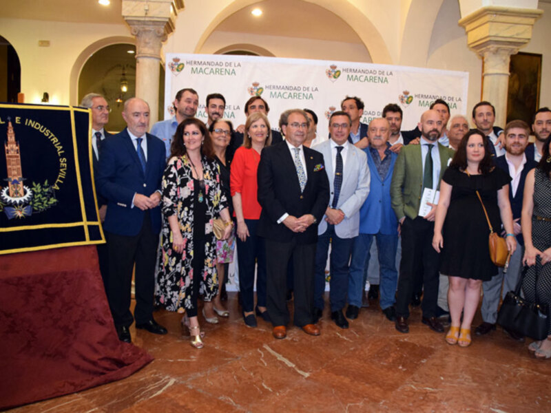 Grupo de personas posando para una foto en el marco de la Hermandad de la Macarena, Sevilla.