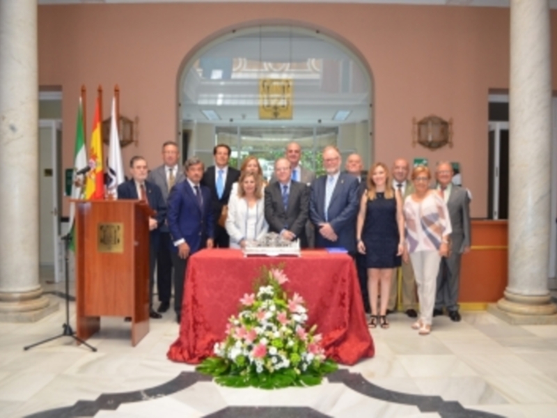 Grupal de personas en una ceremonia oficial en un salón con columnas y banderas.