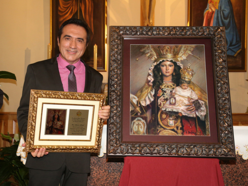 Persona en traje con marco dorado y retrato de Virgen con niño, en un entorno religioso.