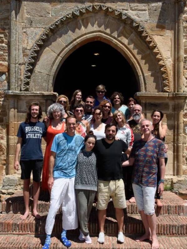 Grupo de personas posando en las escaleras de un edificio histórico con arco de piedra.