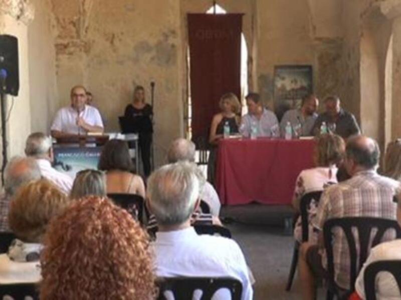 Una conferencia de prensa en un edificio histórico, con un panel de personas en el escenario y un público asistente sentado en sillas.