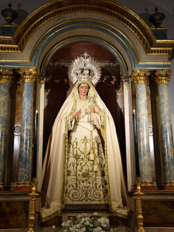 Imponente imagen de la Virgen María en un altar ornado con detalles dorados y columnas.