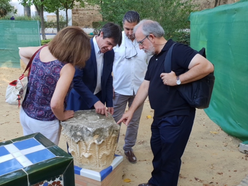 Gente examinando un antiguo pedestal en un entorno arqueológico.