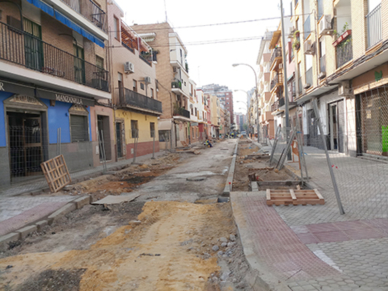 Estructura de una calle en construcción, con trabajos de pavimentación y edificación en proceso.