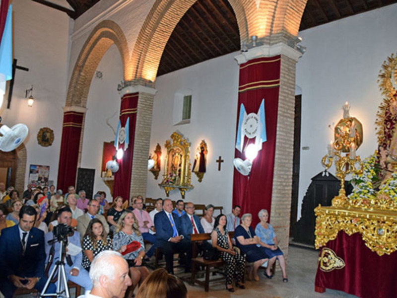 Celebración religiosa en una iglesia con una procesión de una imagen venerada y un público asistente.