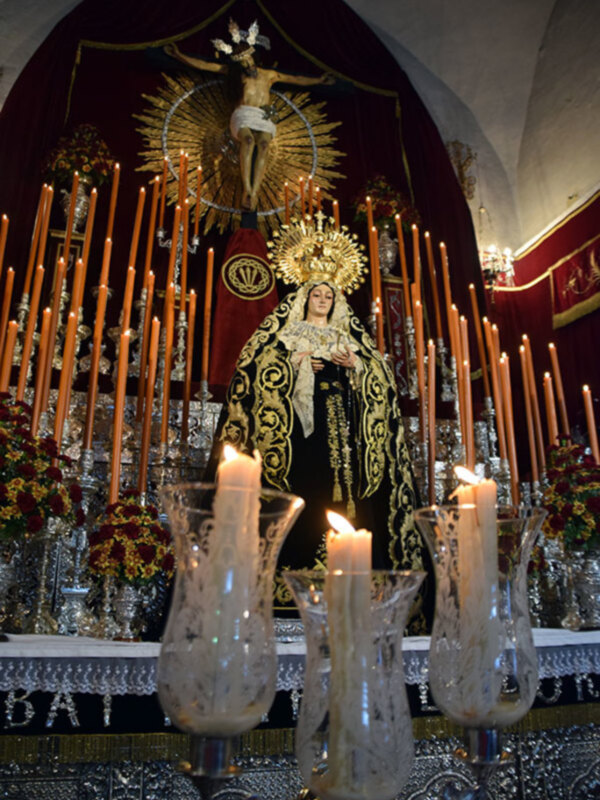 Imaginación de la Virgen María en una iglesia, rodeada de velas y adornos festivos.