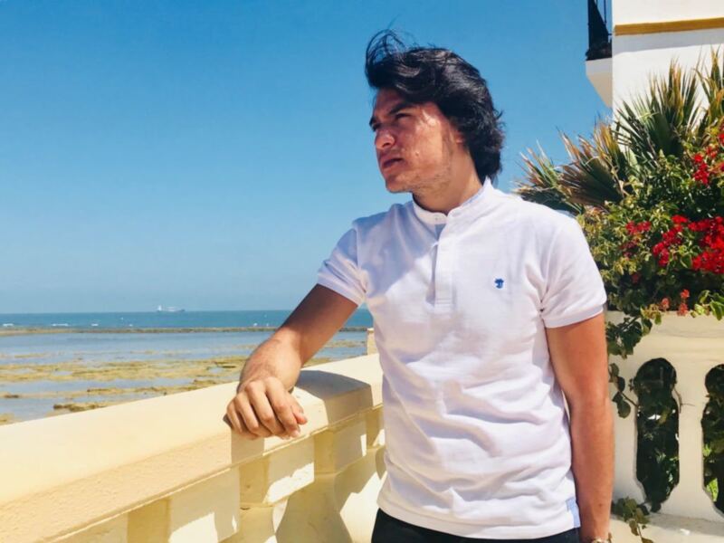 Un hombre en una terraza con vistas al mar, disfrutando del clima soleado.